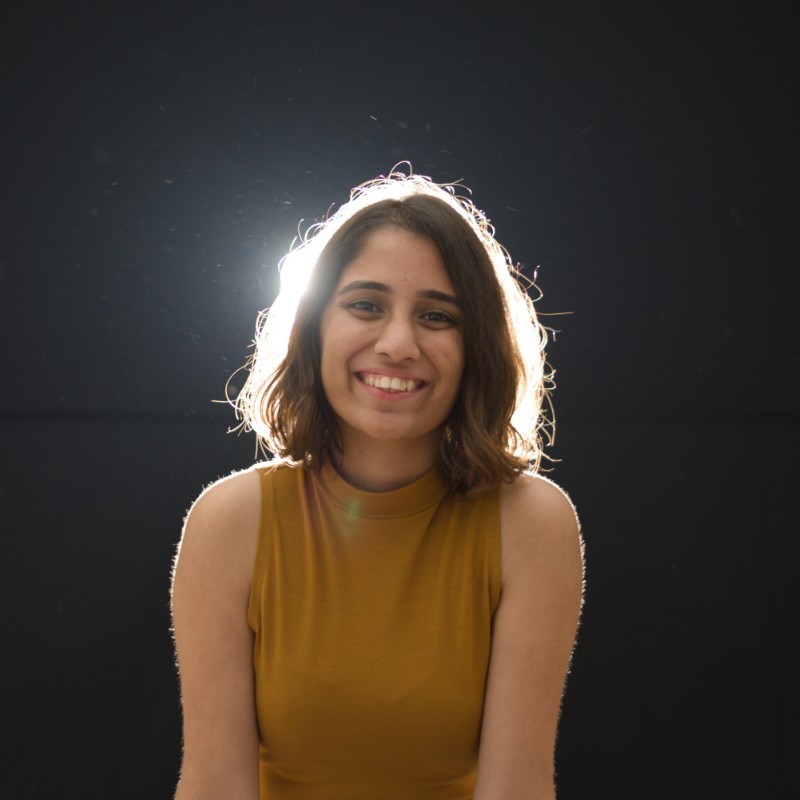 a smiling person in a tank top, backlit
