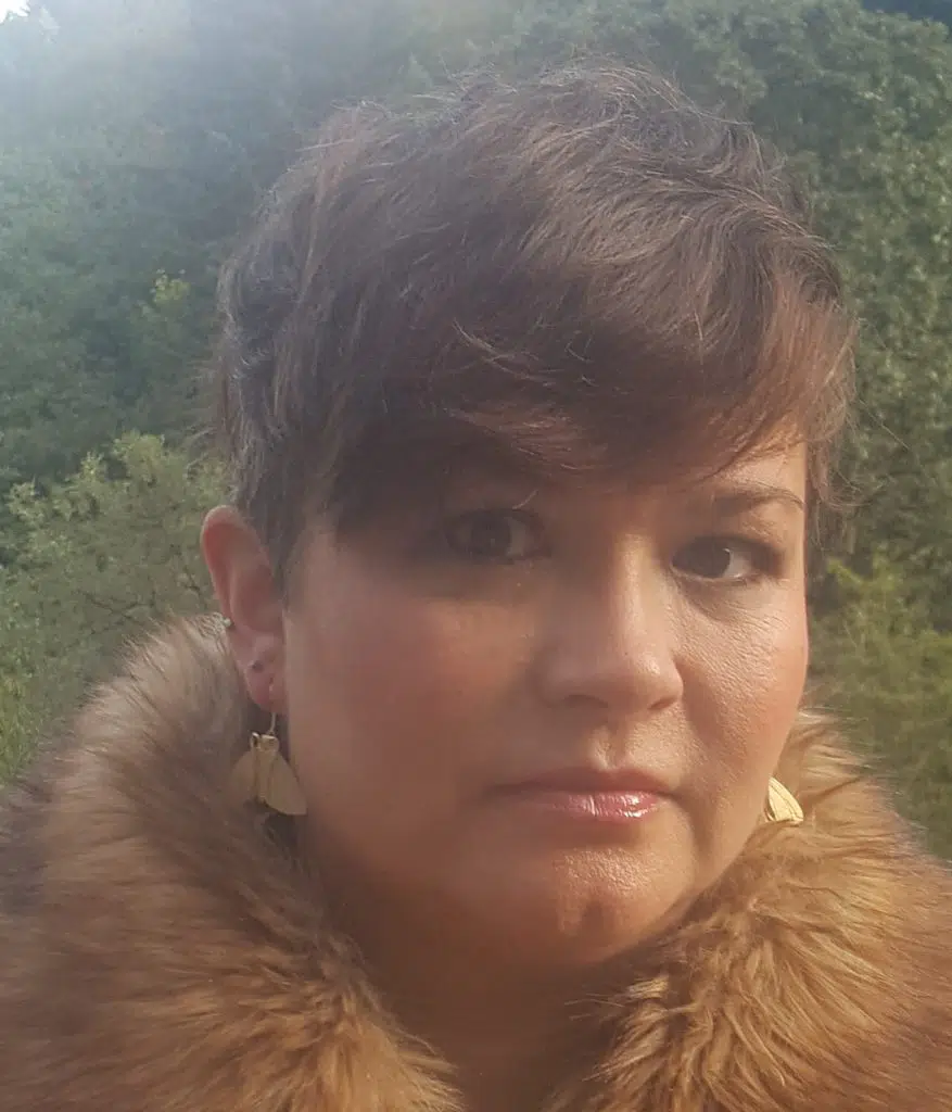 a person with short brown hair and earrings